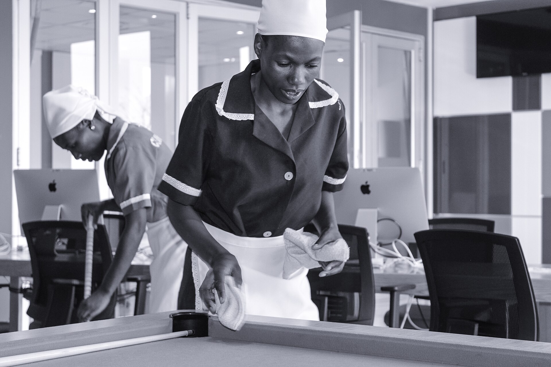 A cleaner wiping down a table in a modern office